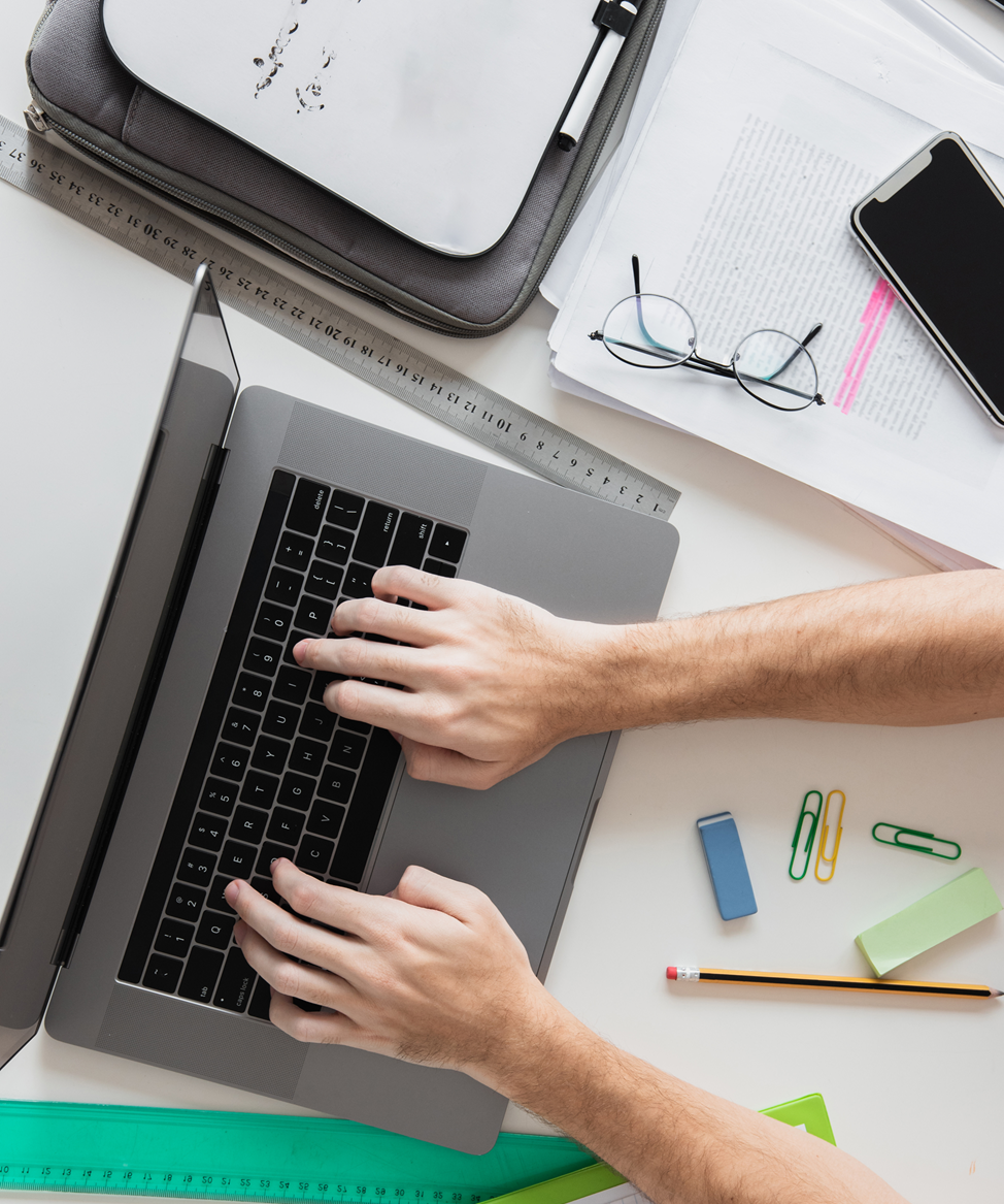 top-view-hands-working-laptop-surrounded-by-stationery-elements